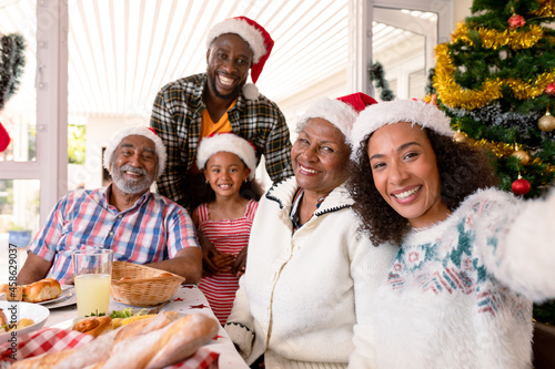 Happy multi generation family wearing santa hats, taking selfie