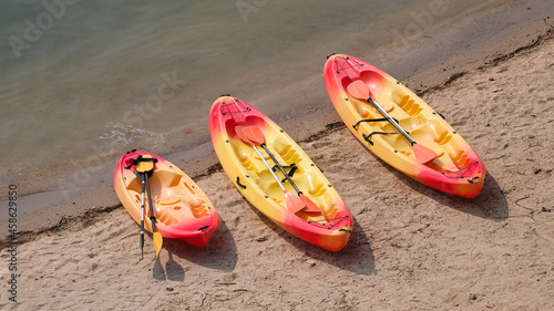 Três barcos a remo parados na margem do rio com os remos dentro - caiaques - cores vermelhas e amarelas - albufeira photo