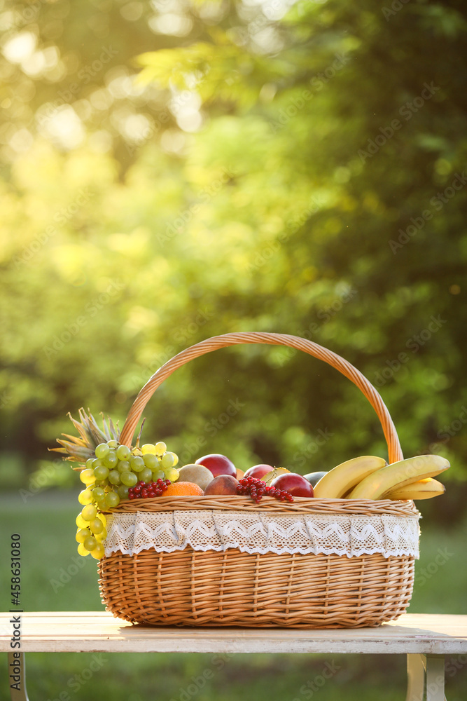 Wicker basket with fresh fruits on table outdoors Wicker basket with fresh fruits on table outdoors