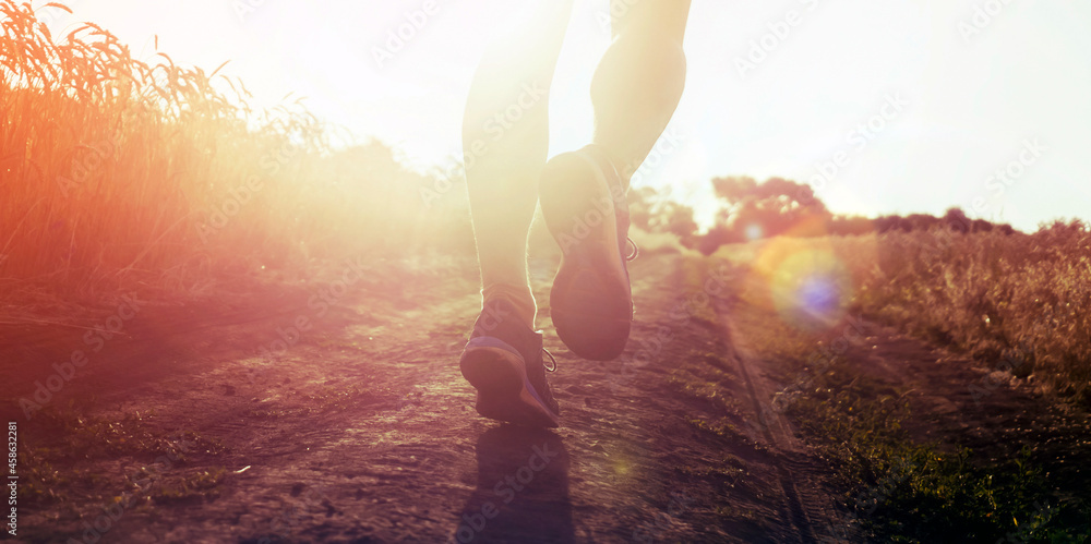 Athlete runner legs running on a close-up of a trail across a field. Athlete runner legs running on a close-up of a trail across a field.