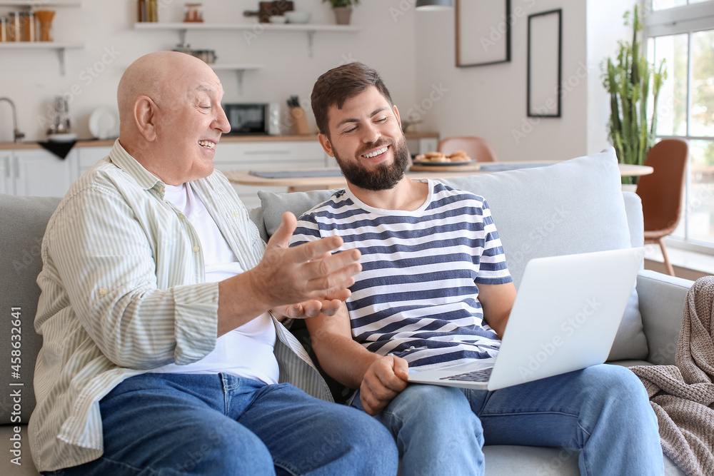 Man and his father with laptop video chatting at home Man and his father with laptop video chatting at home