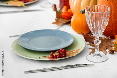 Festive table setting with glass, rowan and autumn leaf on white tablecloth