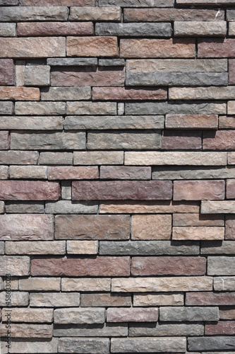 Full frame close-up view of a building wall with natural stone in various colors