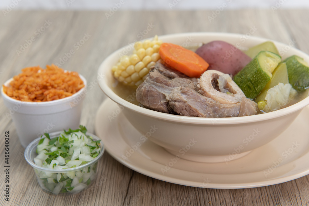 Hearty bowl of Caldo de res Mexican beef stew hot from the stove and served with rice and pico de gallo Hearty bowl of Caldo de res Mexican beef stew hot from the stove and served with rice and pico de gallo