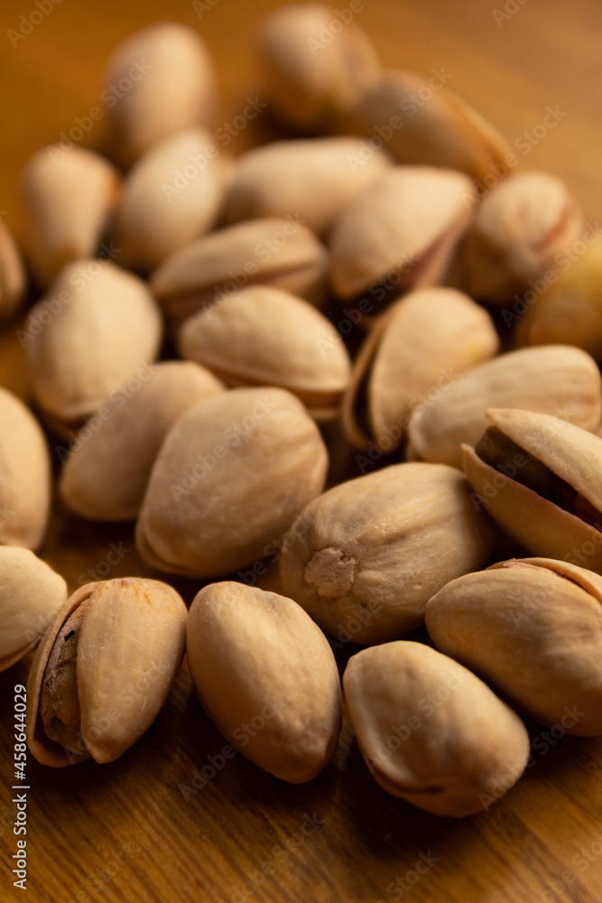 close up of many pistachios on a wooden background