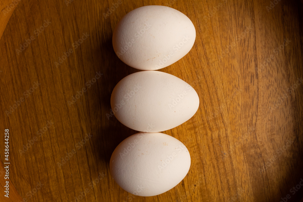 three white eggs on a wooden background three white eggs on a wooden background