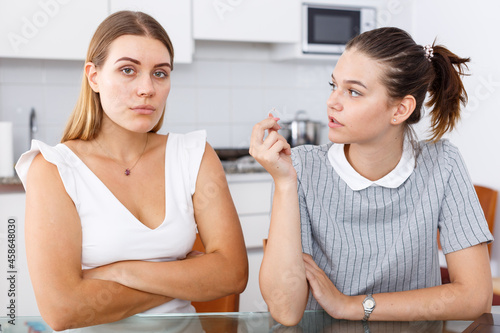 Fotografie Young girl showing betrothal ring to upset female friend at home