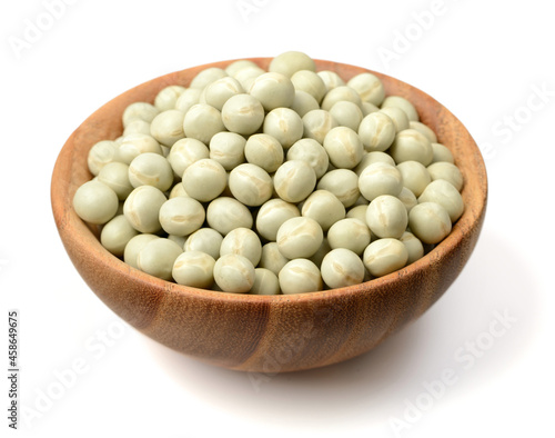 uncooked dried green peas in the wooden bowl, isolated on the white background