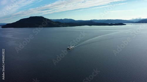 Car and passenger ferry ytteroiningen crossing open sea underway between Sydnes and Utbjoa - Electric zero emission ferry distant aerial overview - Noway photo