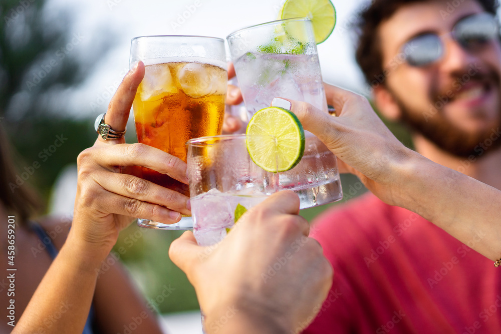 Fototapeta premium Group of young friends toasting outdoors. Focus on glasses, blurred faces.
