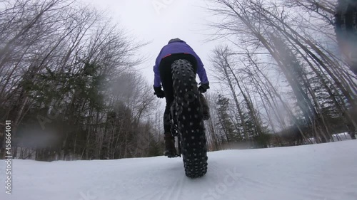 Biking in winter on fat bike. Woman fat biker riding bicycle in the snow in winter. Close up action shot of fat tire bike wheels in the snow. People living active winter sports lifestyle. photo