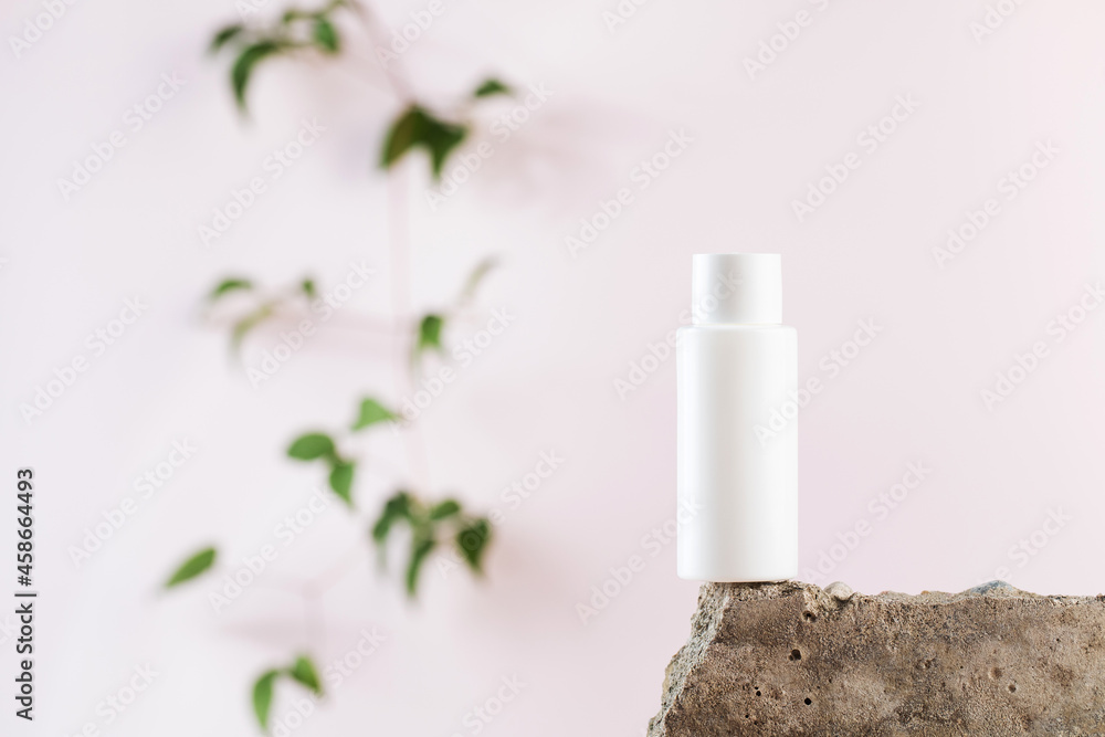 White empty bottle of cosmetics on a concrete podium on a pink background close-up. Copy space. White empty bottle of cosmetics on a concrete podium on a pink background close-up. Copy space.