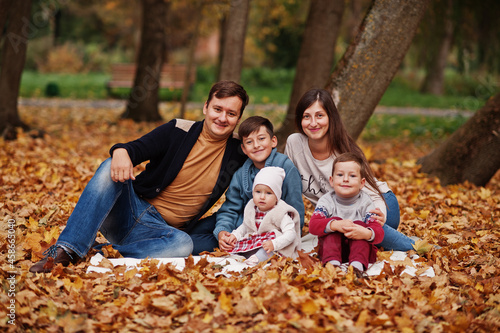 Happy family at autumn leaves park. Three kids.