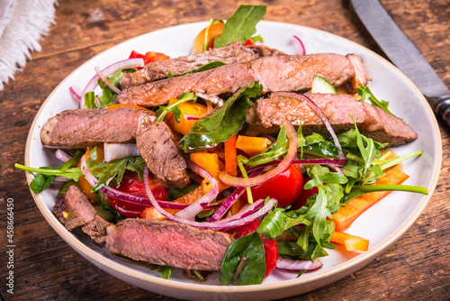 Healthy vegetable salad with beef steak on a plate, rustic style, close-up.