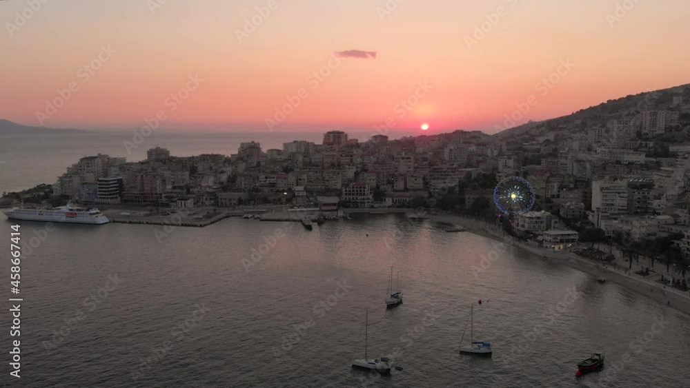 Slow aerial forwards at sunset in harbor city with ferris wheel and boats Slow aerial forwards at sunset in harbor city with ferris wheel and boats