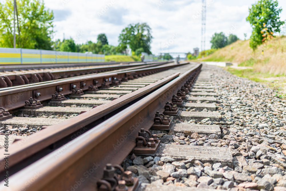 Naklejka premium Railway track details closeup photo with selective focus.Close-up view of railway bolts.Summer day details of railway