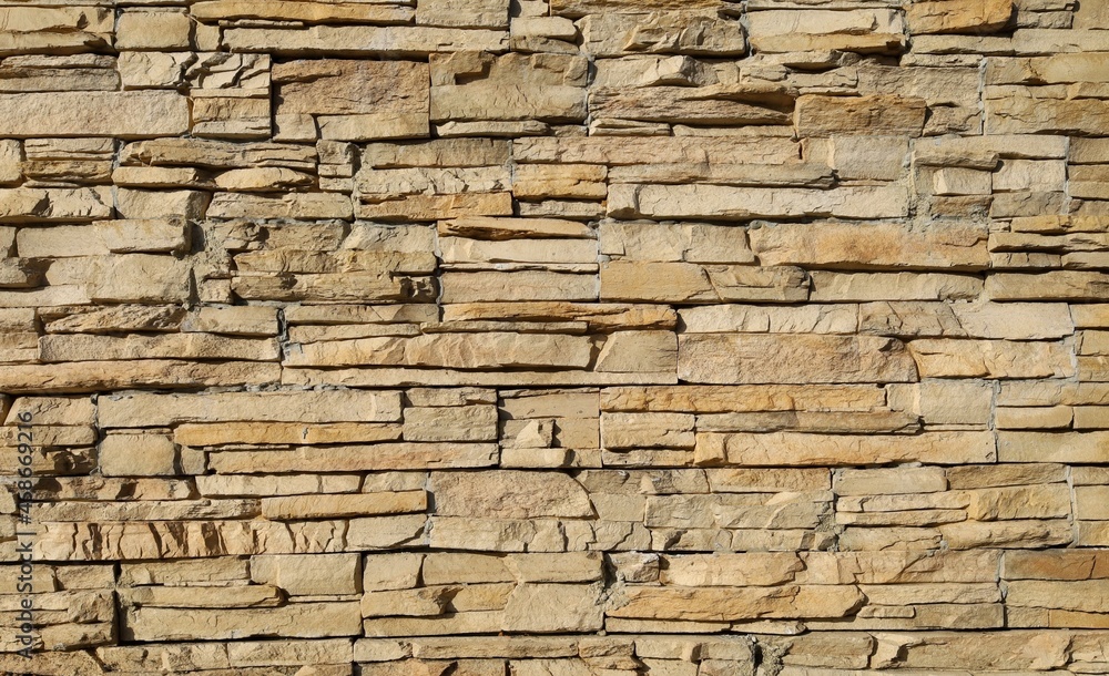 Stone cladding wall made of striped stacked slabs of natural brown rocks. Background and texture. 