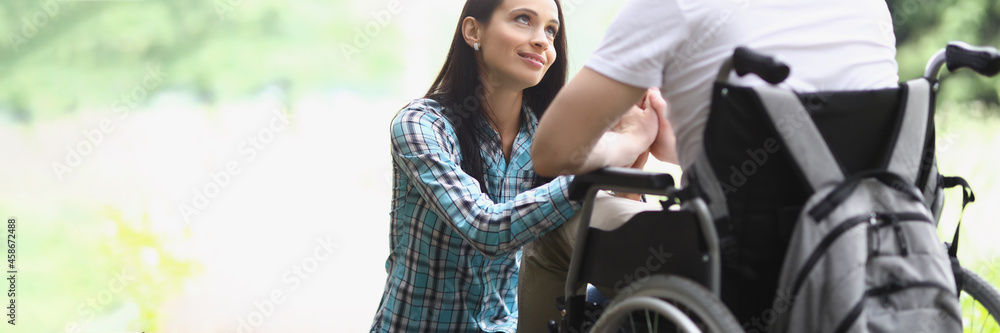 Woman looks with loving gaze at man in wheelchair