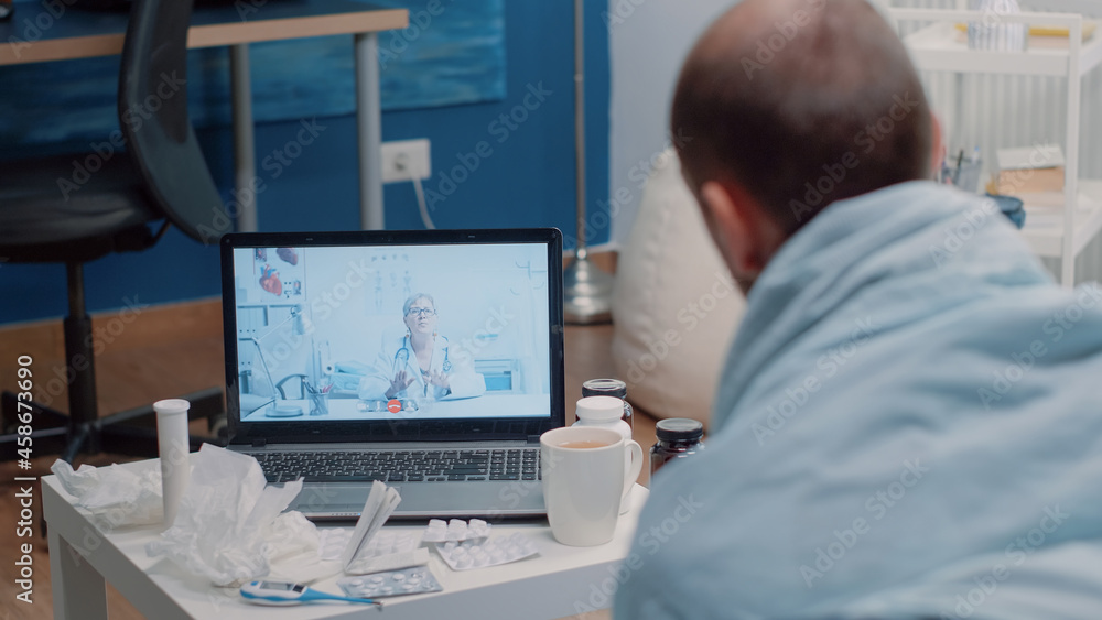 Sick man using video call telemedicine for consultation, asking about cold and flu symptoms and treatment against disease. Patient talking to medic on online remote conference to cure pain