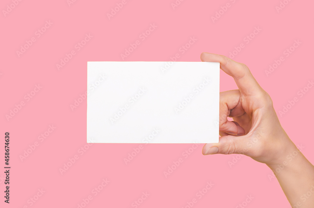 White card in a female hand on a pink background. Female hands with business card White card in a female hand on a pink background. Female hands with business card