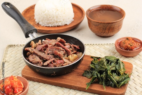 Se'i Sapi or  Beef Sei is Indonesia Traditional Smoked Beef, Served with Boiled Cassava Leaves and Sambal Luat or Sambal Matah. Typically Food from Nusa Tenggara, Indonesia