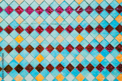 Multi-coloured worn shiny tiles. Bright decorative glazing bricks exterior, elegant house wall outdoors.