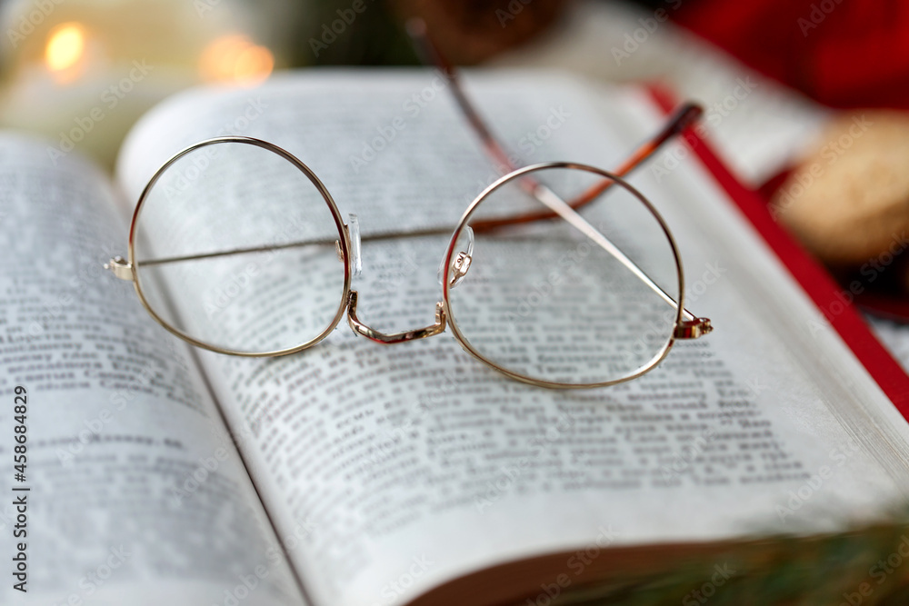reading, holidays and leisure concept - close up of open book and glasses on christmas reading, holidays and leisure concept - close up of open book and glasses on christmas