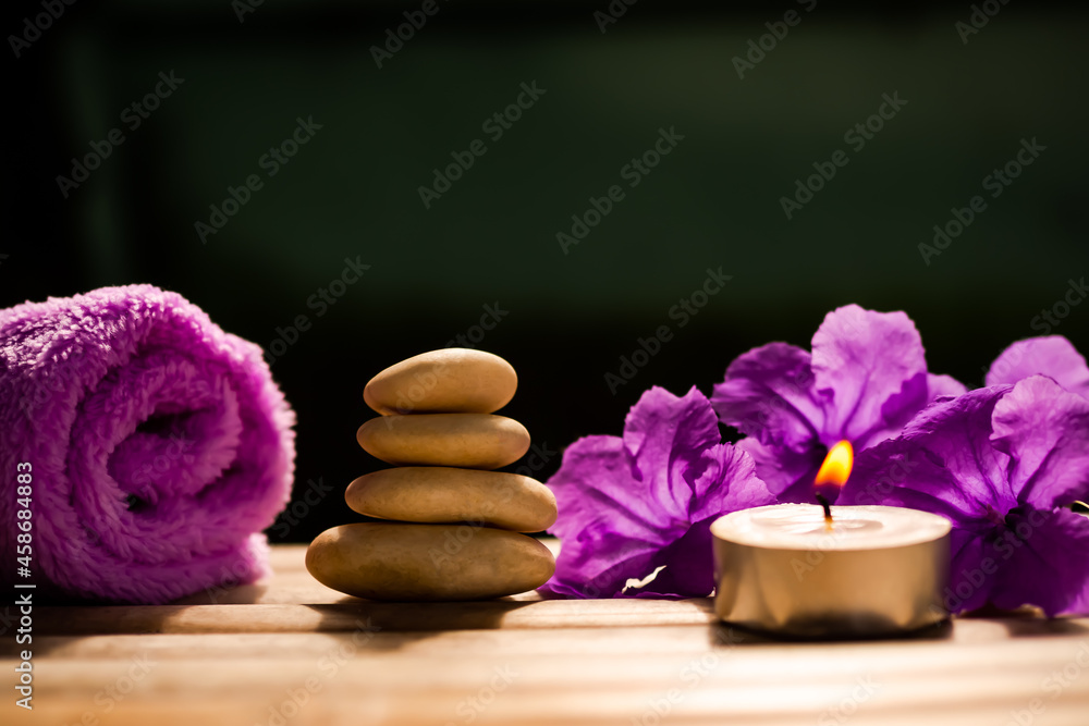 Light candle with stack zen pebbles stone and towel, flowers on wooden with black background. aroma therapy spa set organic herbal for vacation in holidays. for luxury bathroom hotel concep. Light candle with stack zen pebbles stone and towel, flowers on wooden with black background. aroma therapy spa set organic herbal for vacation in holidays. for luxury bathroom hotel concep.