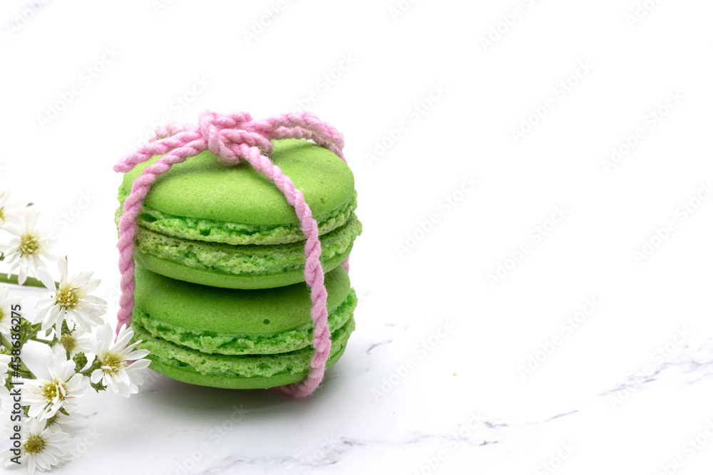 Closed up of two green macaroons tied with soft pink thread with beautiful tiny white flowers. Closed up of two green macaroons tied with soft pink thread with beautiful tiny white flowers.