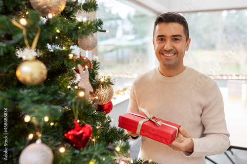 christmas, people and holidays concept - happy smiling middle aged man with gift box at home photo