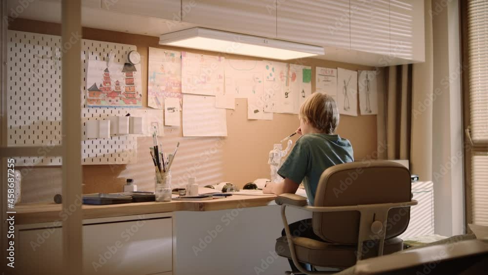 Little boy focused on work. Painting robot skeleton in his room. Rear view Little boy focused on work. Painting robot skeleton in his room. Rear view