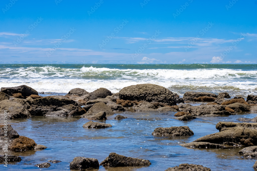 Beautiful rocky stone beach with blue sky and water waves landscape view