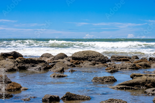 Beautiful rocky stone beach with blue sky and water waves landscape view © Xookits