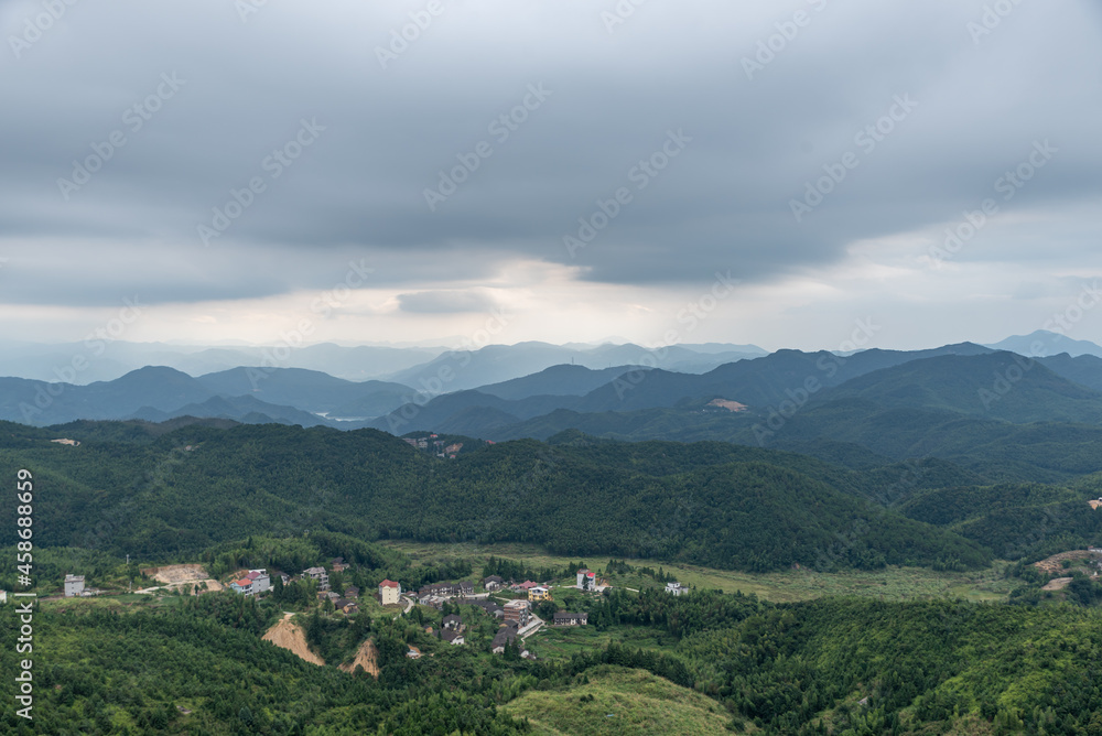 A country surrounded by forests on a cloudy day