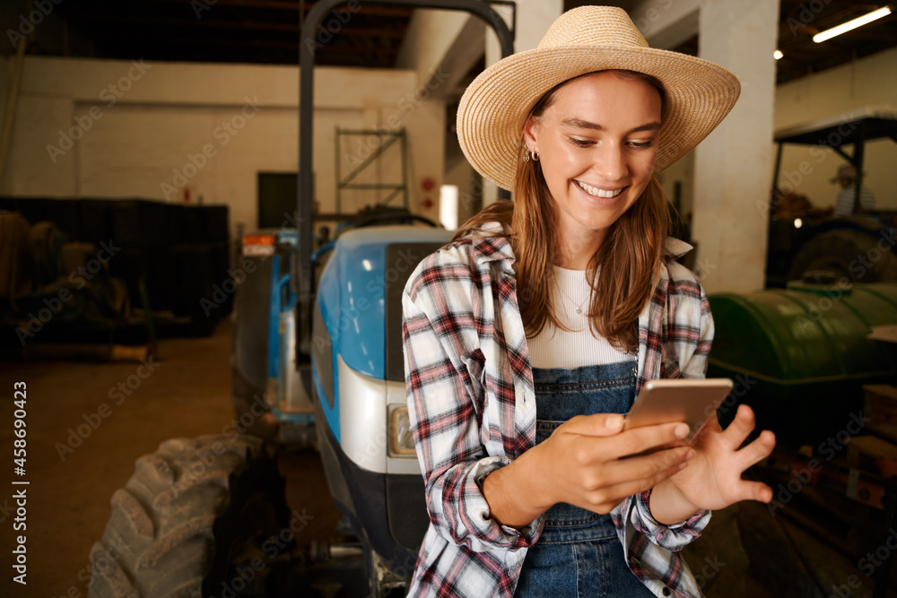Caucasian female farmer texting on cellular device sitting on tractor