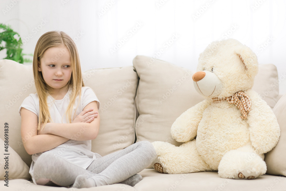 Photo of sad blond girl looking at teddy bear. Photo of sad blond girl looking at teddy bear.