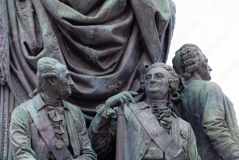 a fragment of a stone sculpture depicting three men in antique doublets and wigs with haughty faces looking into the distance and talking a fragment of a stone sculpture depicting three men in antique doublets and wigs with haughty faces looking into the distance and talking