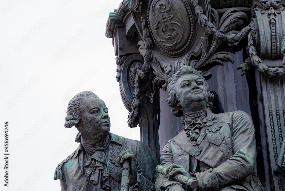 a fragment of a stone sculpture depicting two men in antique camisoles and wigs with haughty faces looking into the distance