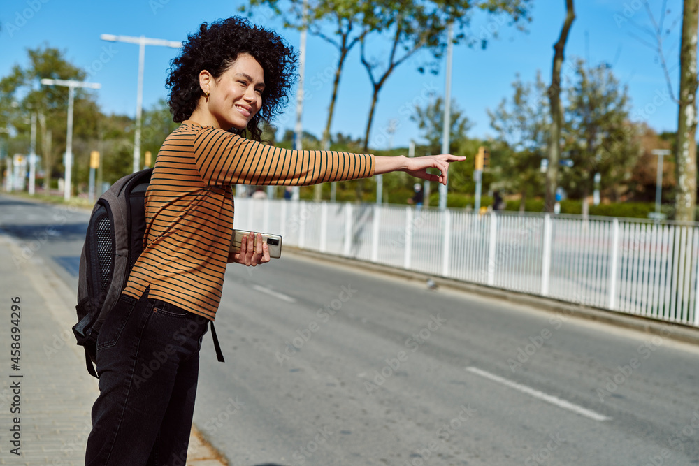 Obraz premium Attractive young woman hailing a taxi by the road