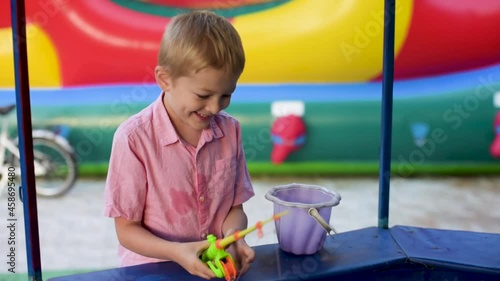 Child catching toy fish in a pool. Little boy fisher catching plastic toy fish on pool amusement park summer day. Little boy have fun on fishing.