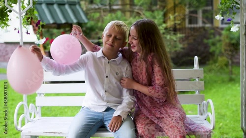 Boy and girl play with balloons in the Park. Children plays in summer park with colorful balloons Happy summer days, vacation, holidays. 