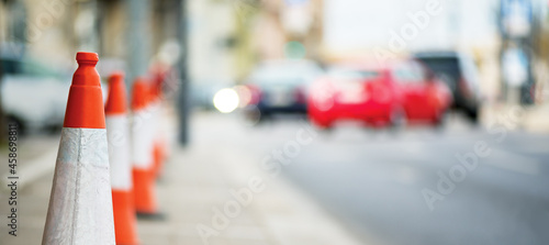 City street space fenced by orange cones, unfocused cars