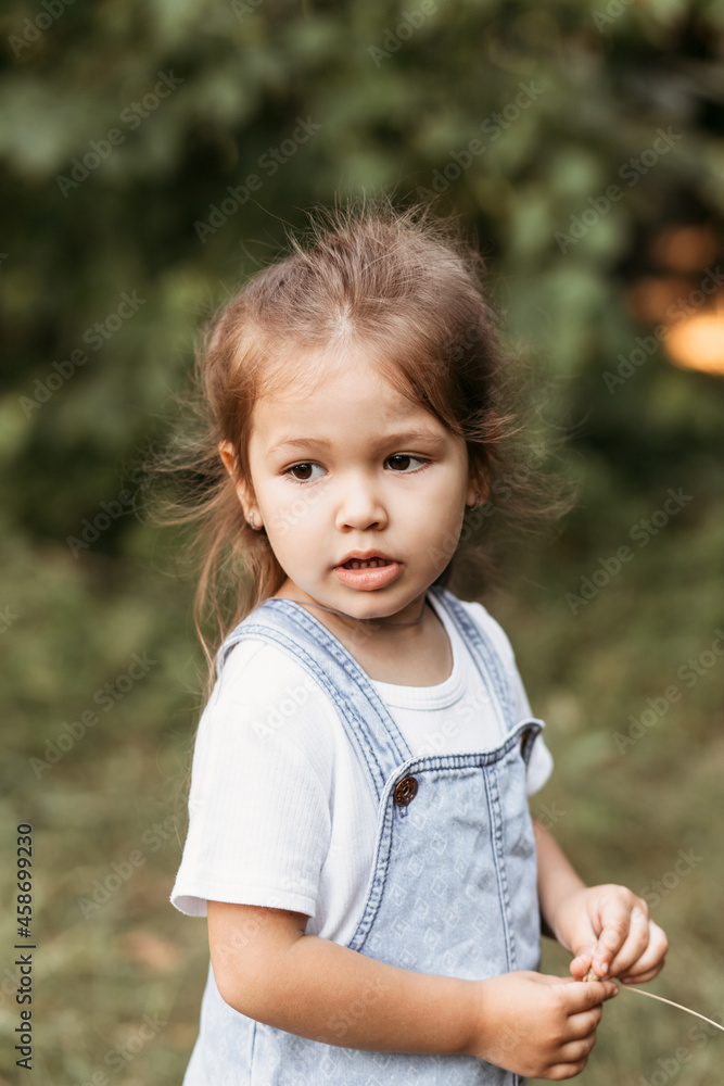 Positive charming little girl enjoying summer sunny day, expression emotions, having fun, happy child walking in summer day Positive charming little girl enjoying summer sunny day, expression emotions, having fun, happy child walking in summer day