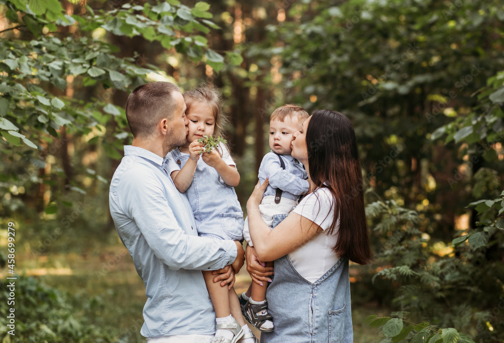 Young happy family with two children in nature in the summer walk. Healthy Smiling Dad, Mom and kids together Young happy family with two children in nature in the summer walk. Healthy Smiling Dad, Mom and kids together