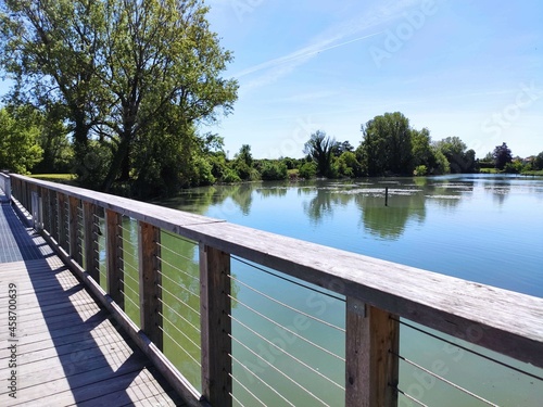 Tableau sur toile Wooden bridge on river Sile water against trees and blue sky, in River Sile Natu
