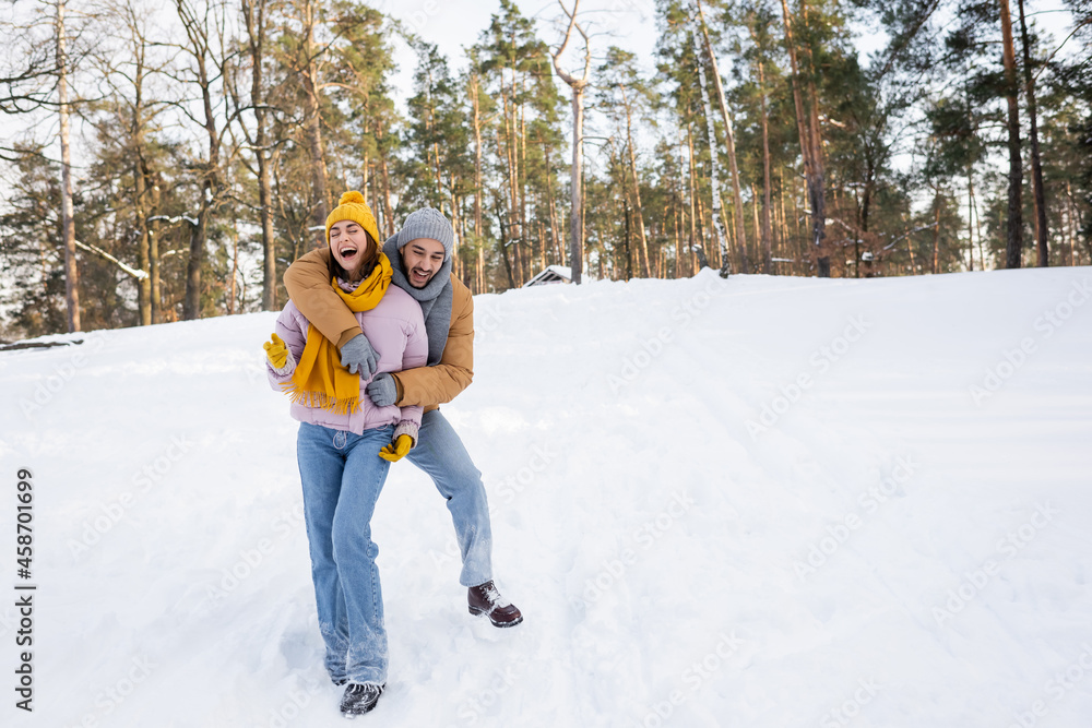 Happy man hugging laughing girlfriend in winter park