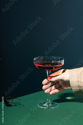 Woman hand holding red champagne in retro glass wine.