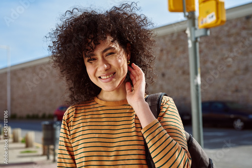 Smiling young woman touching her hair outdoors