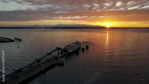 Aerial shot of ferry loading passengers with glowing sunset behind it. photo