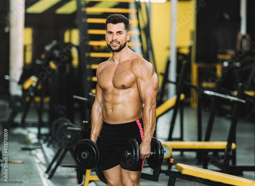 Portrait of a fit man holding dumbbells in a gym